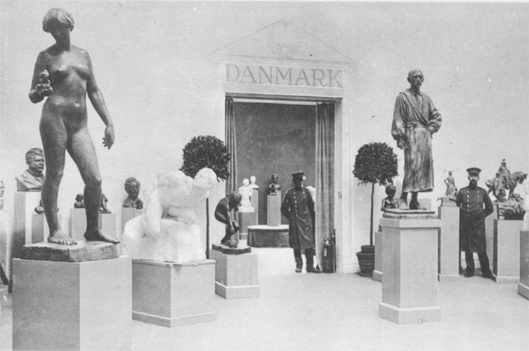 Svart-vitt äldre fotografi taget i en utställningssal. I salen syns en mängd olika statyer gjorda av sten, föreställande människor.