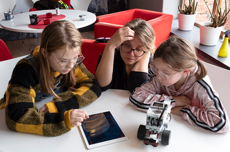 En kvinna och två flickor bygger en lego-robot.