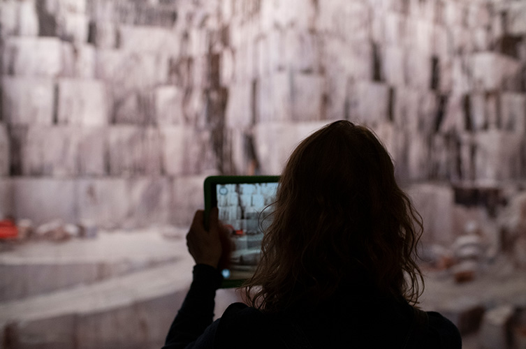 Kvinna som tittar på ett stort fotografi genom en ipad.