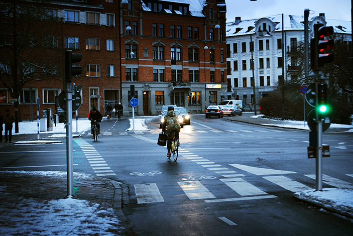 Person cyklar vid ett övergångställe med mycket snö i bakgrunden
