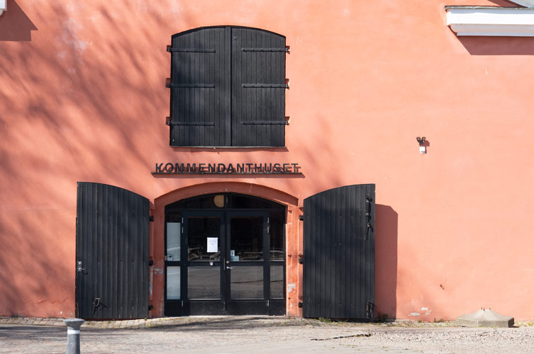 Kommendanthuset har en putsad fasad och tidstypiska träportar.