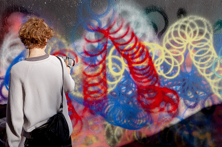 En person som står och målar graffitti. 