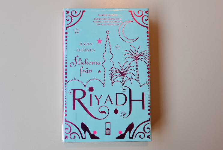 Bokomslag i blått och siluett av en stad i en stil som kopplas till mellanöstern med palmer och ett torn. Boktiteln och författaren står i rosa text.