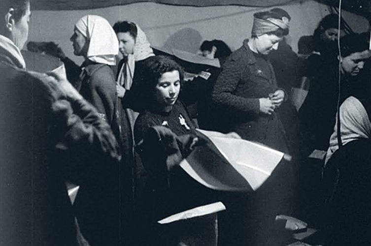Äldre svart-vitt foto på några kvinnor, i mitten sitter en kvinna i klänning.