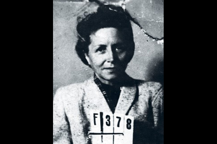 Äldre svart-vitt porträttfoto, kvinna i kavaj med nummerlapp framför bröstet.
