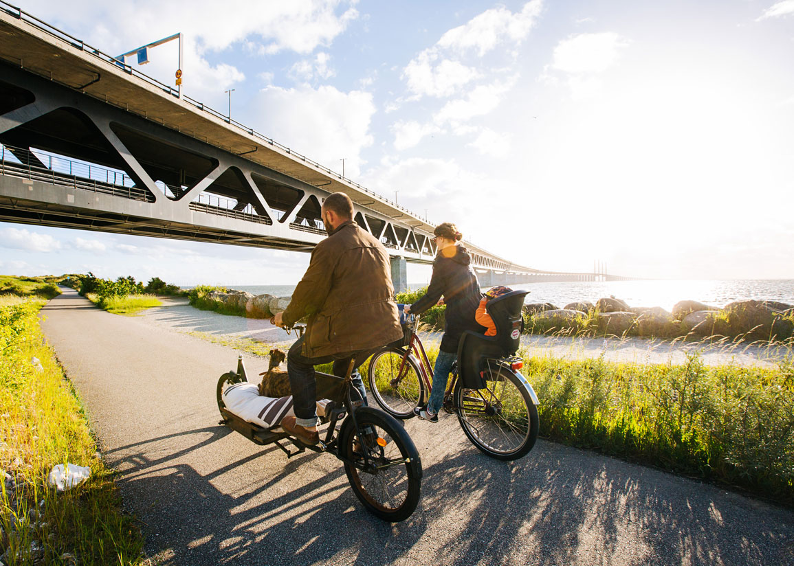 Cyklister på väg mot Öresundsbron i solsken.