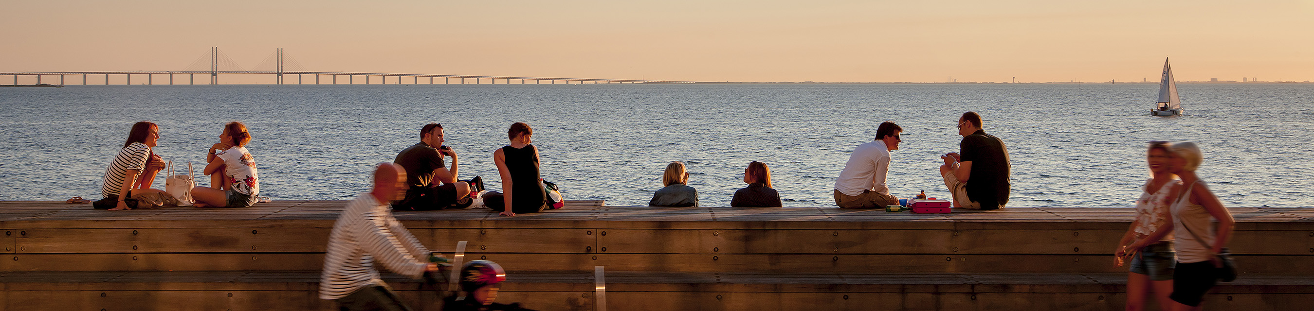 Personer sitter i Västra Hamnen vid solnedgången