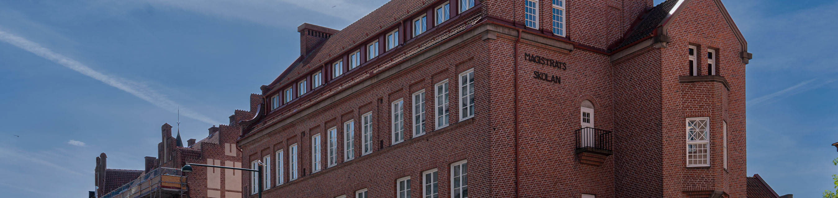 En äldre röd tegelbyggnad med många vita fönster.