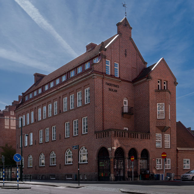 En äldre röd tegelbyggnad med många vita fönster.