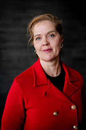 Karin Karlsson i röd kavaj och uppsatt hår. 