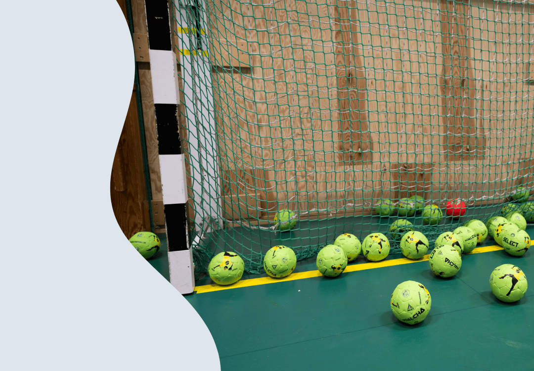 Foto på flera handbollsbollar som ligger i ett mål.