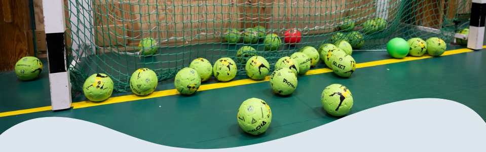 Foto på flera handbollsbollar som ligger i ett mål.