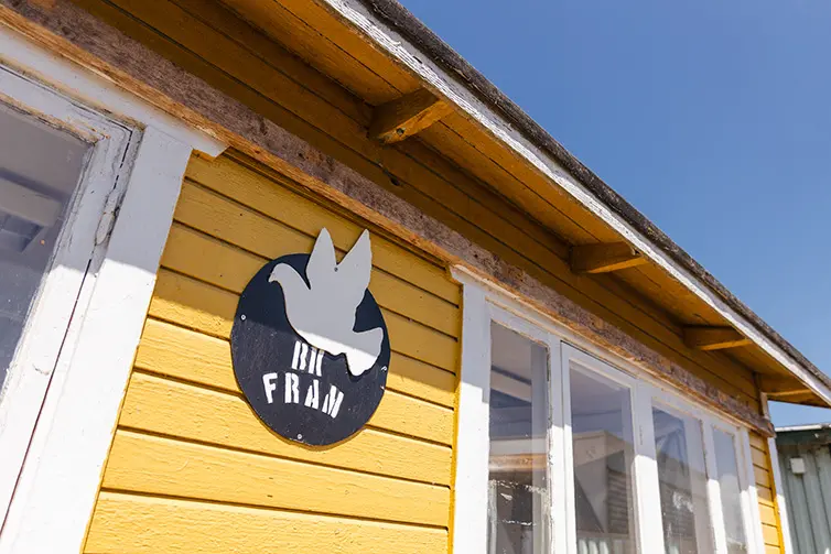 En gul kolonistuga med en grön trädgård på Fram brevduveklubb.