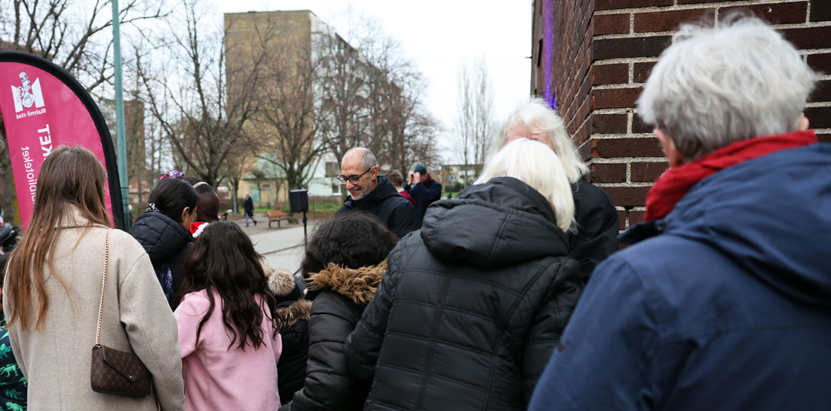 Glad man med en samling människor i olika åldrar framför sig.