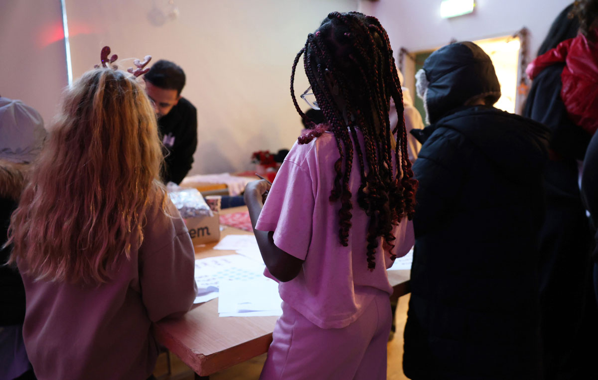 Barn pysslar vid bord med fritidsledare.