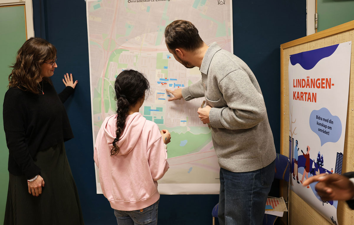 En kvinna, ett barn och en man pratar och pekar på en karta.