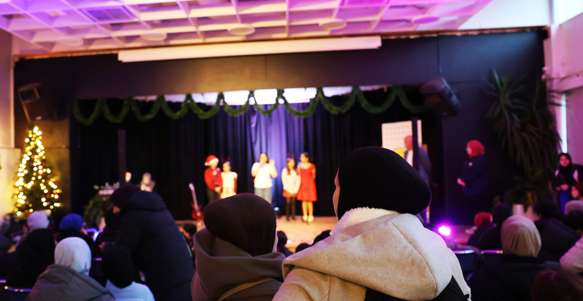 En juldekorerad scen med julklädda barn och publik.