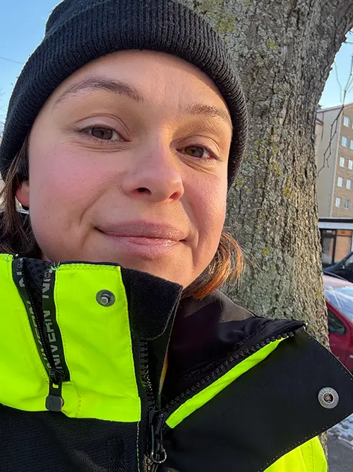 Ida Örnberg i svart mössa och varseljacka framför ett träd.