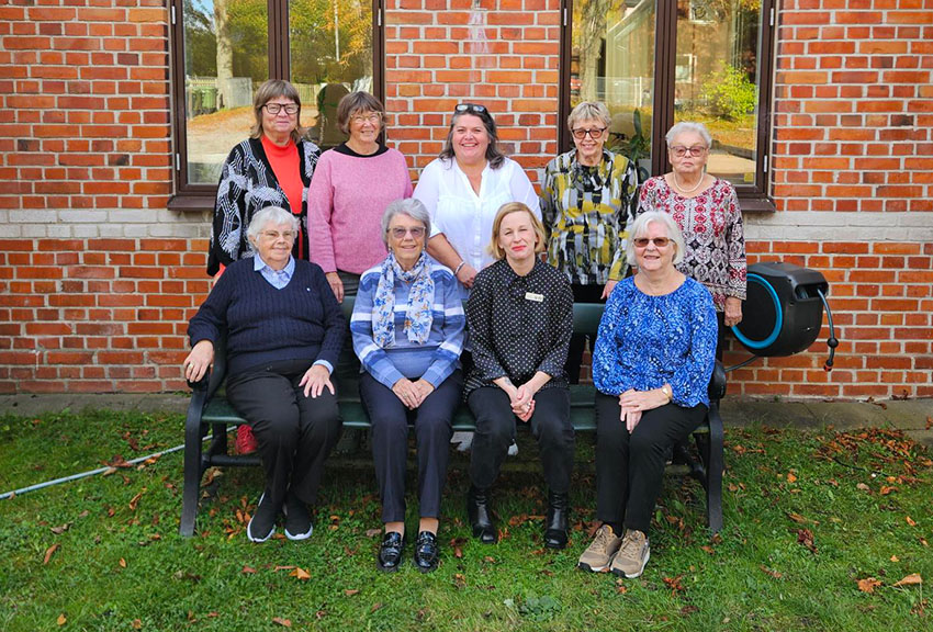 Deltagarna står och sitter i rader utanför mötesplatsen.