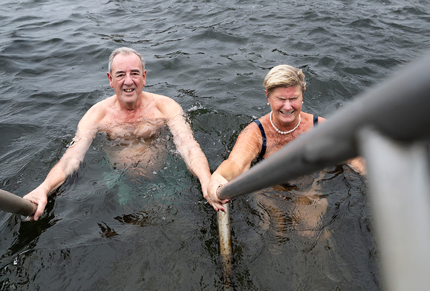 Ingemar och Mia står i vattnet och håller i räcket.