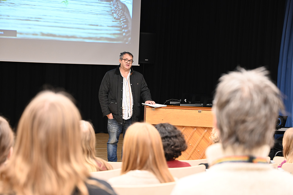 Louis Zyto, står framför eleverna i aulan och berättar. 