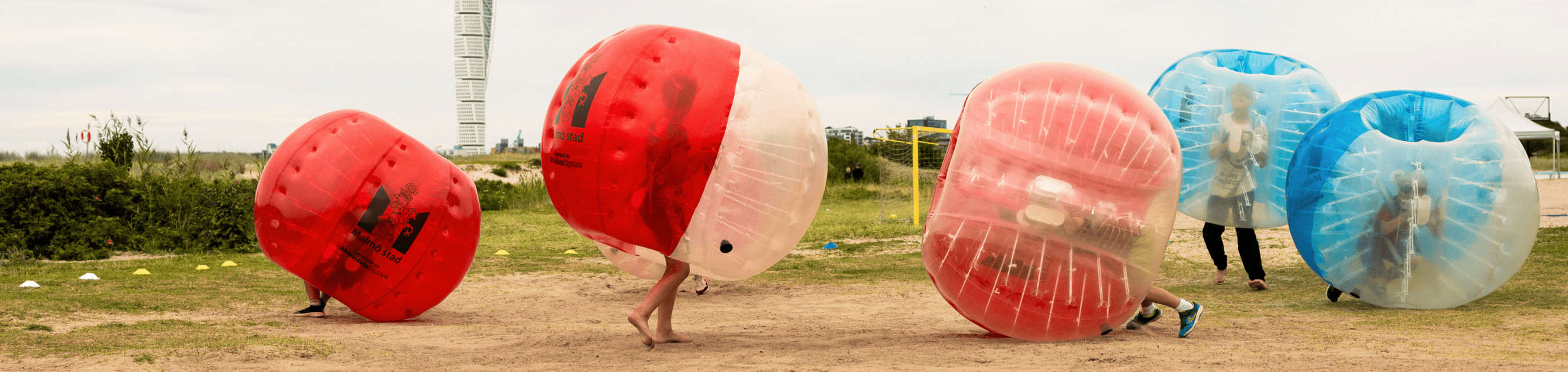 Fyra personer använder bubble balls på Ribersborgsstranden i Malmö. Turning Torso syns i bakgrunden.
