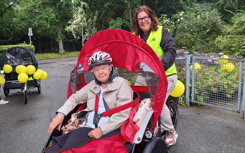 Äldre kvinna i cykelvagn som körs av hennes dotter.