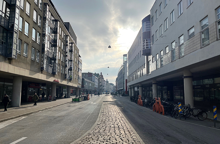 Fotografi av del av Södra Förstadsgatan. På bilden syns byggnader som reser sig vid sidorna av vägen. Gatan sträcker sig långt framåt.