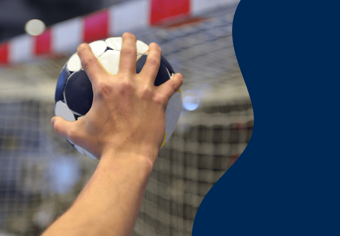 Inzoomat foto på en hand som håller en handboll framför ett handbollsmål.