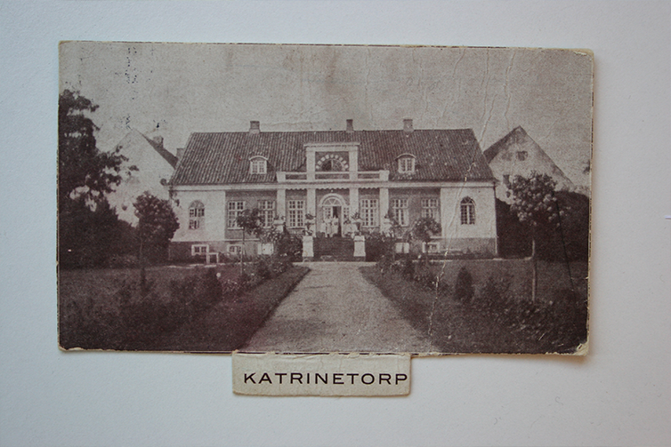 Gammalt åldrat svartvit foto av Katrinetorps huvudbyggnad upphängt på en vägg.