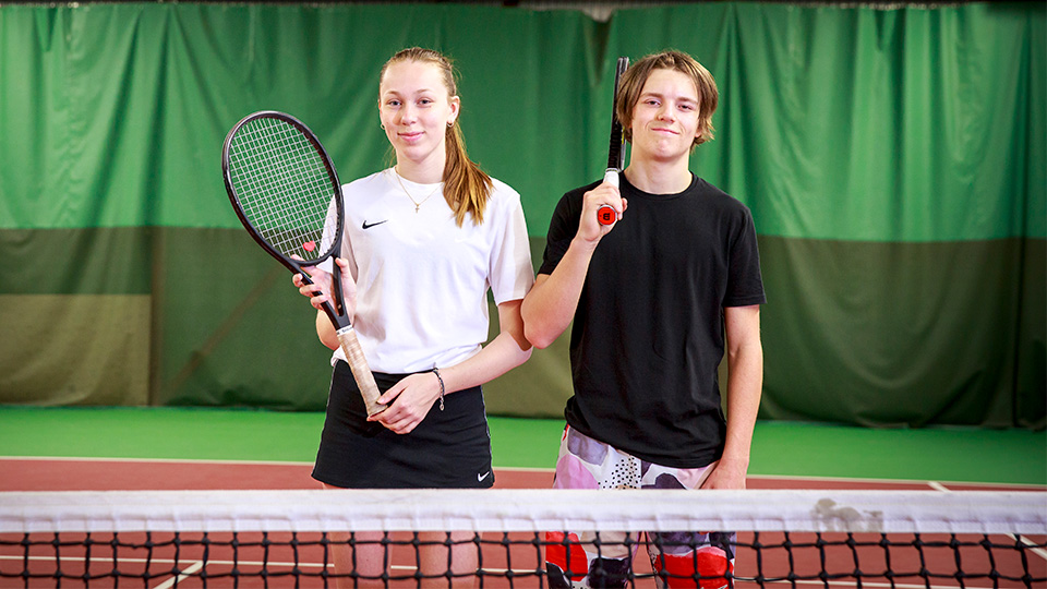 En tennistjej och en tenniskille på banan.