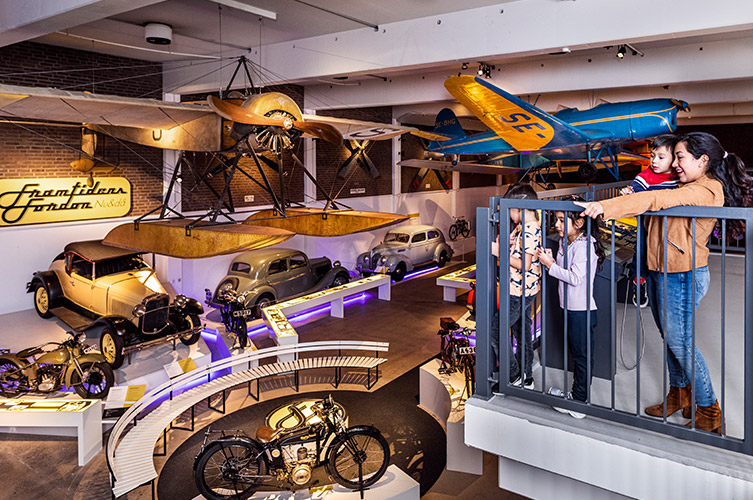 BIldspel från utställningshallen. HÄr finns äldre fordon, bilar, cyklar, mc och en gammal brandbil samt flygplan hängandes i taket. Utställningen är populär bland barn i alla åldrar, det går bra att klättra och leka i vissa av fordonen.