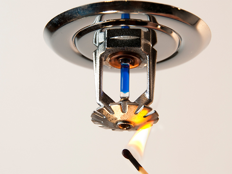 Någon testar sprinklersystemet genom
  att hålla upp en tändsticka med låga under sprinklern.