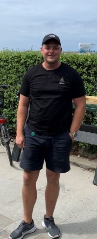 Man står med svart keps, shorts och tröja med Malmö stads logga vid Ribersborgsstrand. 