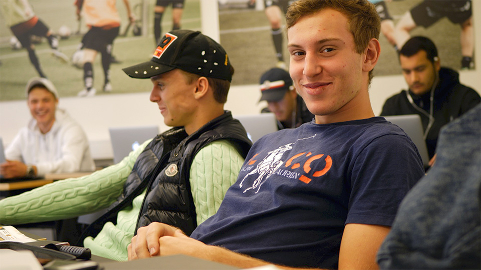 Två killar sitter vid sina bänkar i klassrummet.