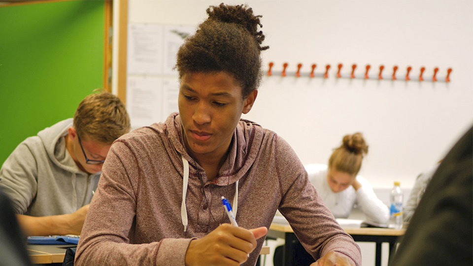 En elev sitter vid sin bänk och arbetar.