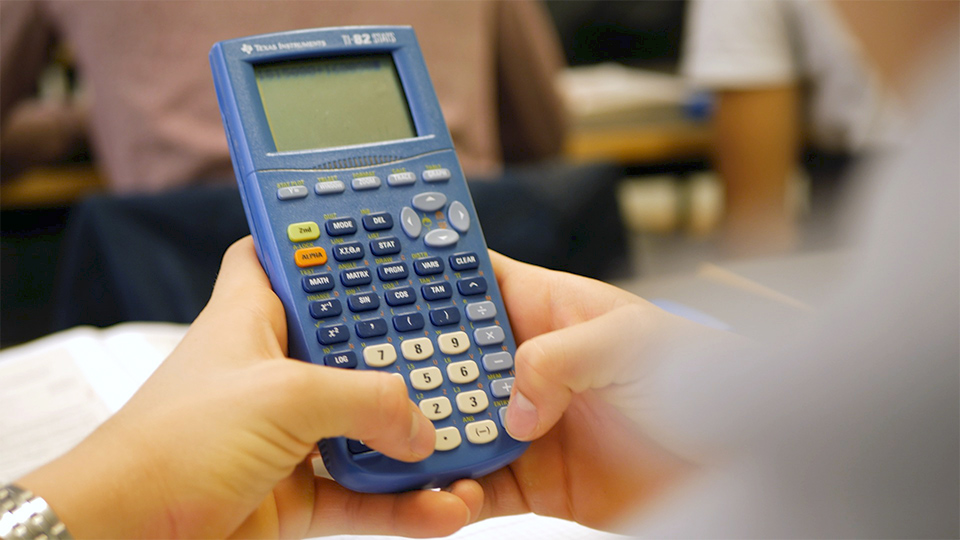 En elevs händer håller i en miniräknare.