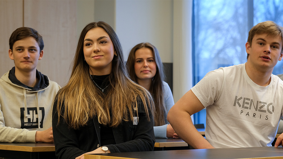 Två killar och två tjejer sitter vid sina bänkar under en lektion.