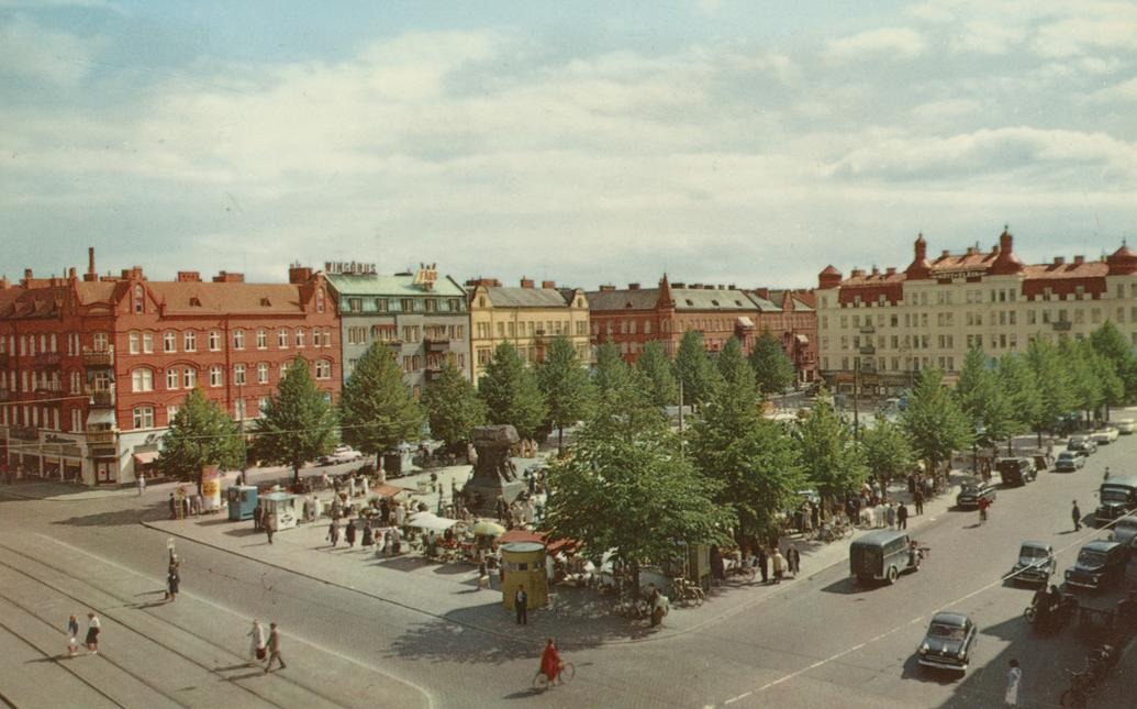 Vy över torg från ovan. På torget syns träd, människor och en skulptur.