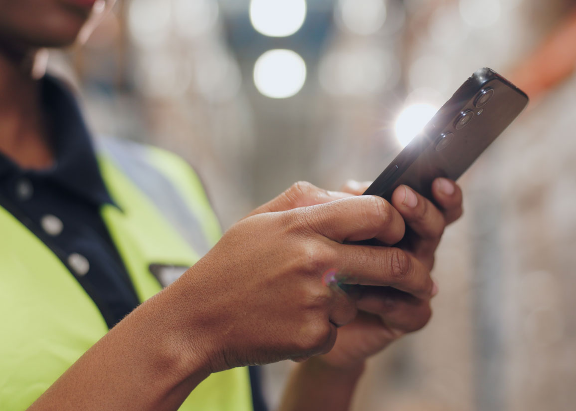 Person med varselväst som håller en mobiltelefon framför sig.