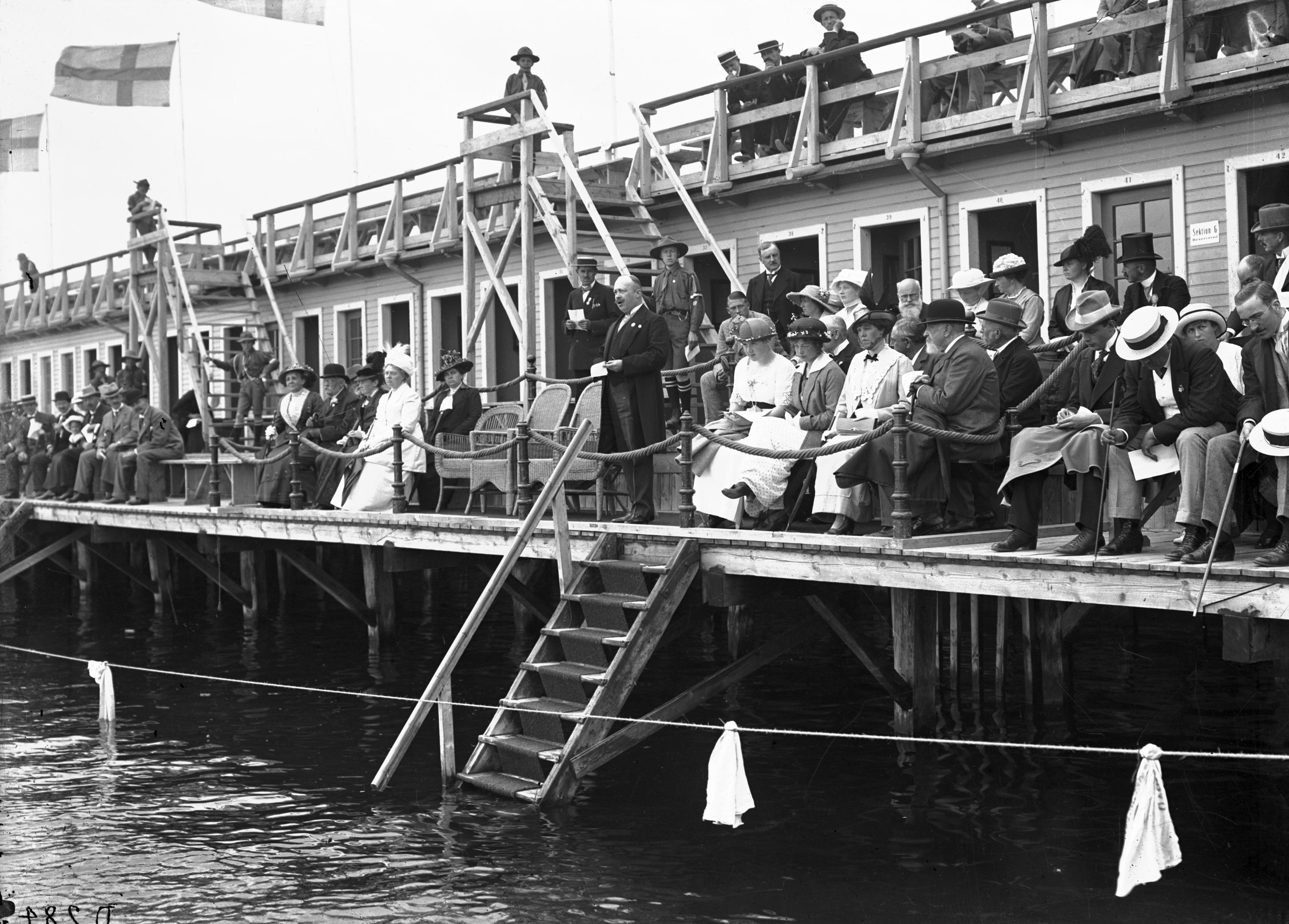 Svartvitt foto av publiken på simuppvisningen inne på kallbadhuset.