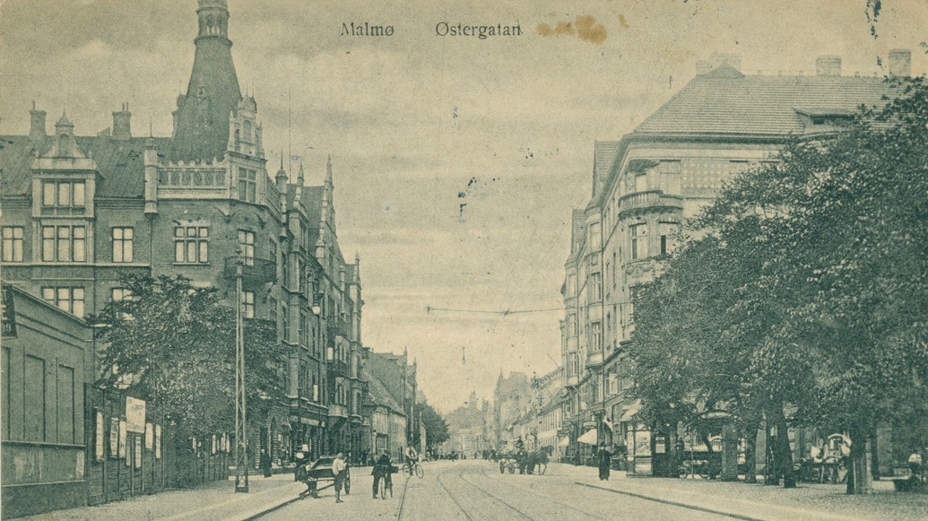 Svartvitt foto av Östergatan taget mitt i gatan med byggnader längs båda sidorna och cyklister och gående.