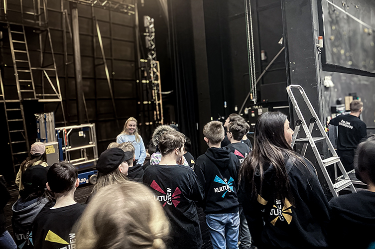 En mängd ungdomar back stage. De har matchande t-shirts med kulturcrew-tryck. 