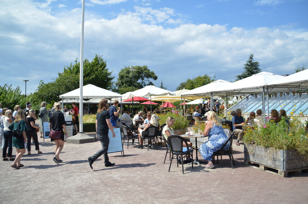 Kafégäster som njuter av solen på uteservering.