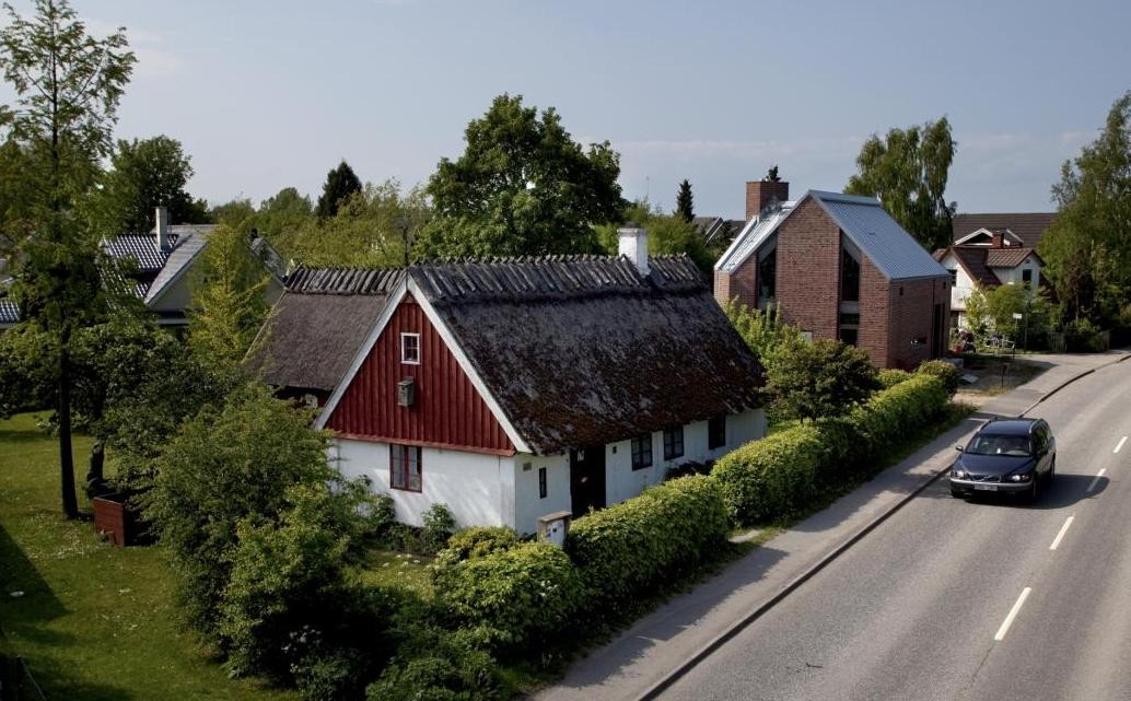 Vitkalkad gård med vasstak i grönskande trädgård.