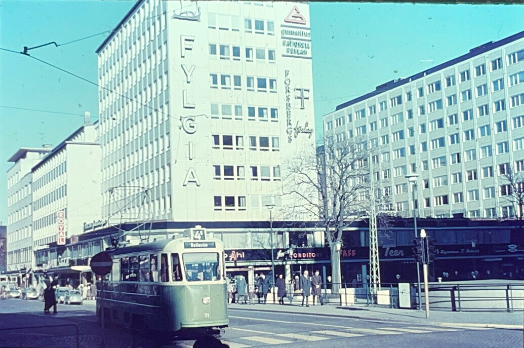 Moderna höga byggnader och en spårvagn i förgrunden.