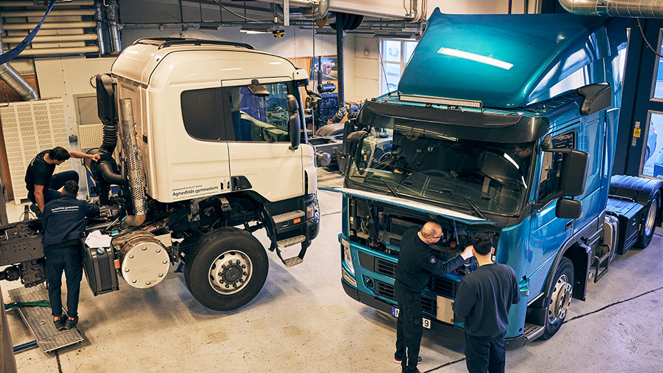 Elever och lärare arbetar på två lastbilar.