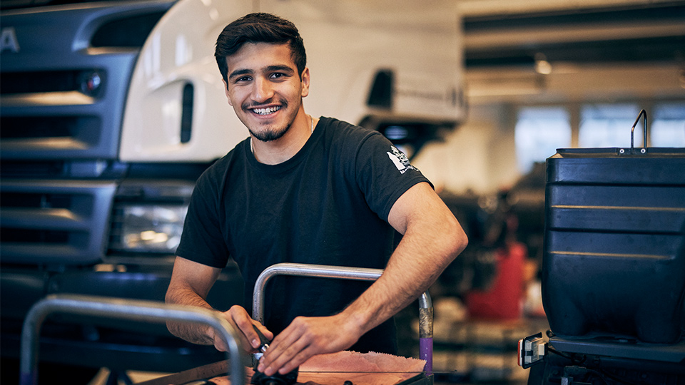 En leende elev framför en lastbil.