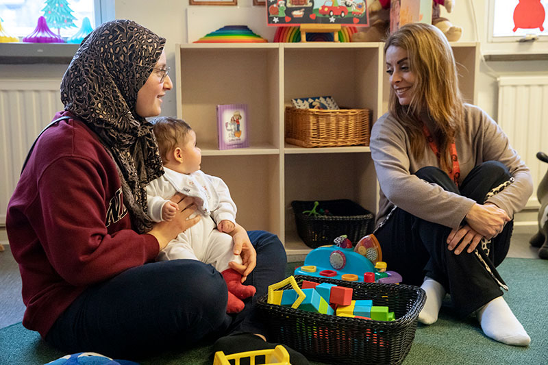 Yasmin Al Khasharfeh och dottern Sila besöker öppna förskolan för att delta i aktiveterna tillsammans, träffa andra barn och föräldrar och träna språket. Förskole­lotsen Ibtisam Alkadi, till höger, berättar för så många föräldrar hon kan om hur viktig förskolan är för barnens utveckling. Foto: Miriam Preis, Vårt Malmö