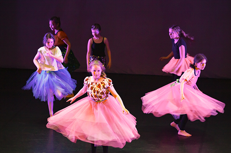 Dansande tjejer i prinsesskjolar på en upplyst scen.